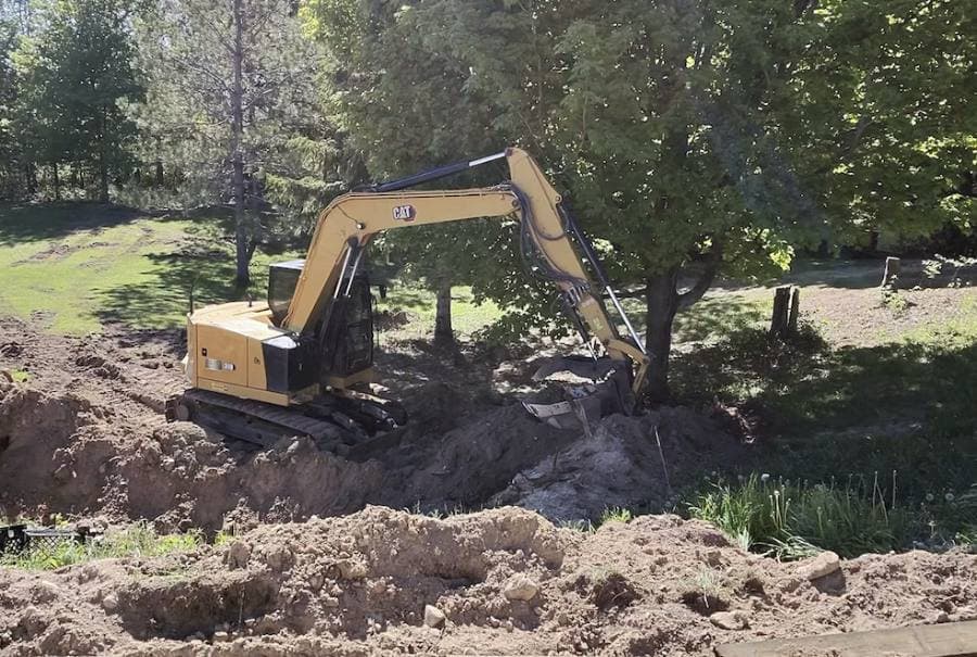an excavator digging the footing trench for a home addition